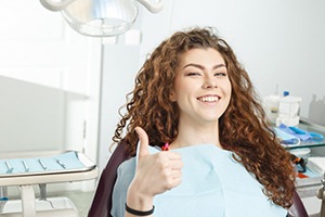 woman giving a thumbs-up in the dental chair 