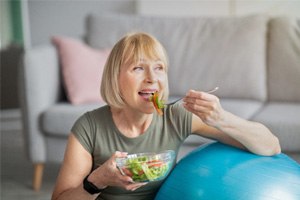 woman eating salad while sitting on couch 