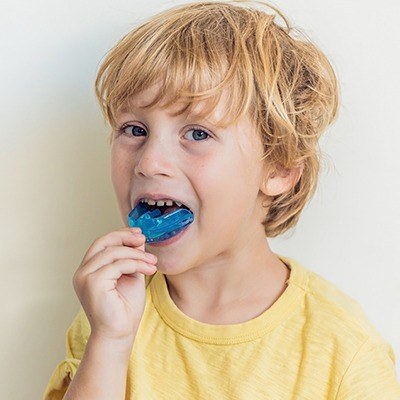 Young boy placing blue mouthguard