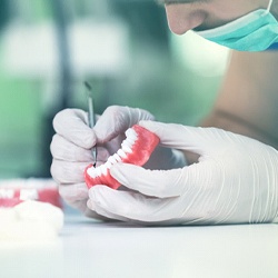Dentist inspecting full dentures in Springfield