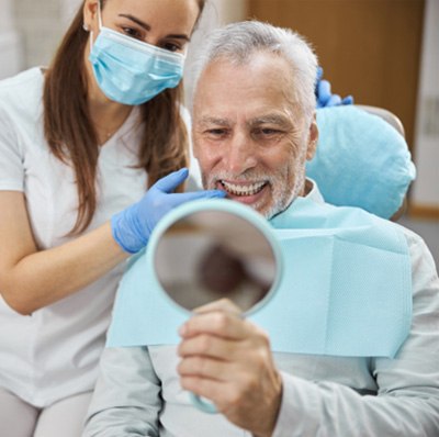 Senior dental patient admiring his teeth in mirror