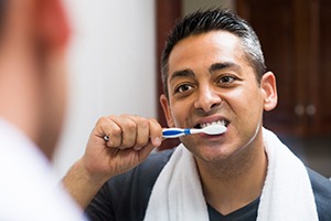 Man brushing his teeth after dental implant surgery in Springfield 