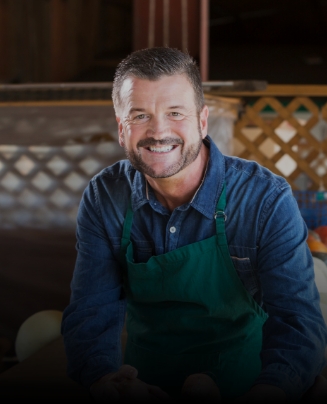 Man in green apron smiling