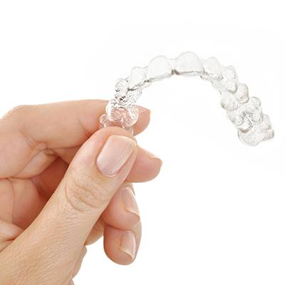 Hand holding a clear Invisalign tray