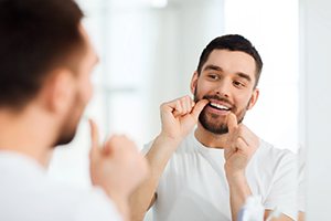man flossing teeth in bathroom