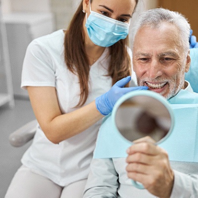 older man looking at mirror in dental chair