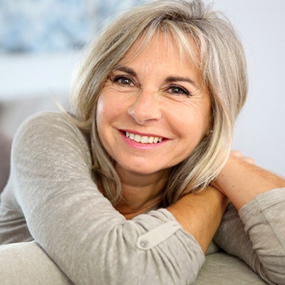 Older woman in grey shirt smiling while sitting