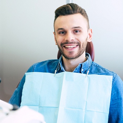 Man in blue shirt smiling in dental chair