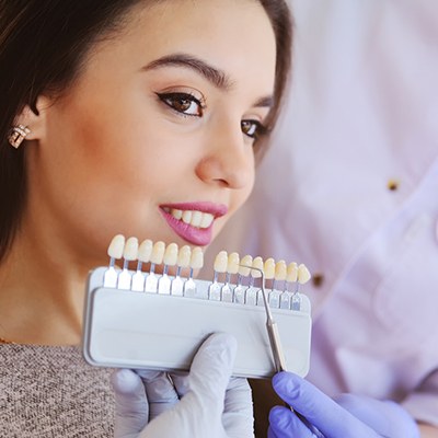 Woman comparing shades of veneers in Springfield with a dentist