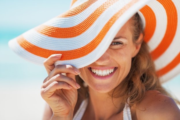 Woman smiling and wearing sun hat during summertime.