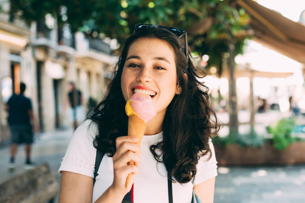 Girl smiling while eating ice cream outside