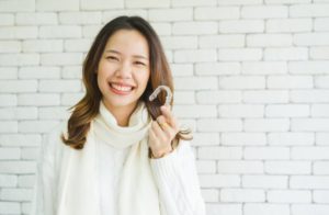 a woman showing her Invisalign tray and smiling