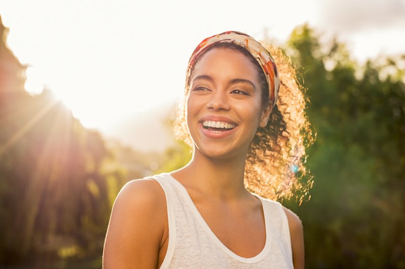 Woman smiles in front of trees.