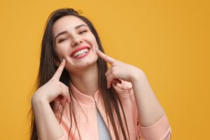 Smiling young woman pointing to her teeth