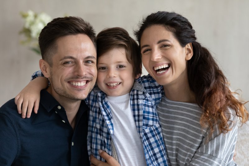 man and woman smiling with their young son