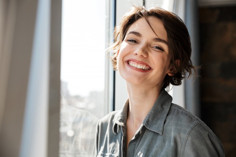 A woman smiling after having her dental crowns replaced